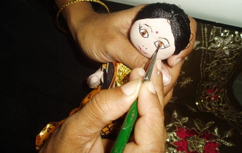 Woman painting eyes on a doll